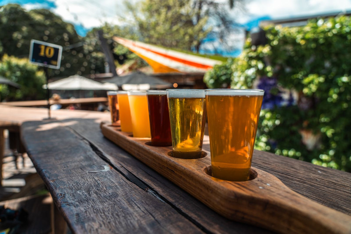 木のトレーに並んだ、色とりどりのクラフトビールの飲み比べ